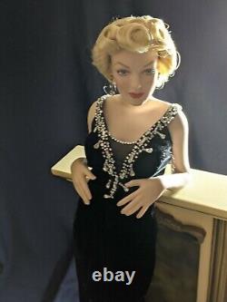 Franklin Mint Marilyn Monroe porcelain doll standing against a Fireplace